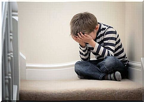 A boy with school phobia sitting on the steps of his home crying.