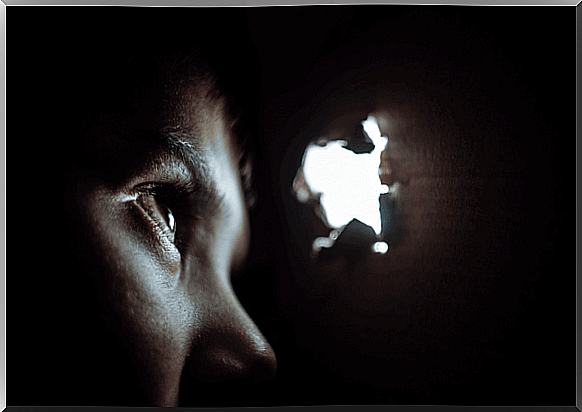 A boy who experiences separation anxiety looks out through a hole in a box