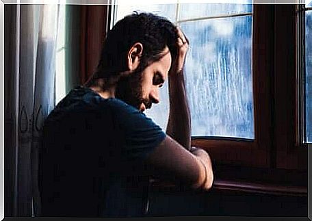 A sad man leaning against a window