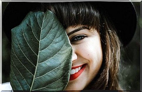 Woman smiling behind a leaf.