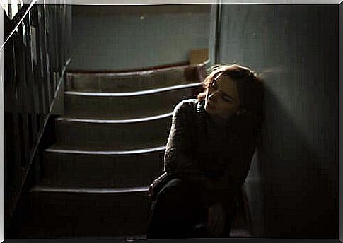 A sad woman leaning against the wall in a stairwell