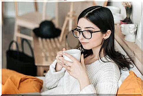 A woman wearing glasses drinking coffee